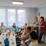 osoby siedzą przy stole i rozmawiają